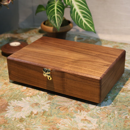 Wooden jewelry box on a floral-patterned surface with decorative items around